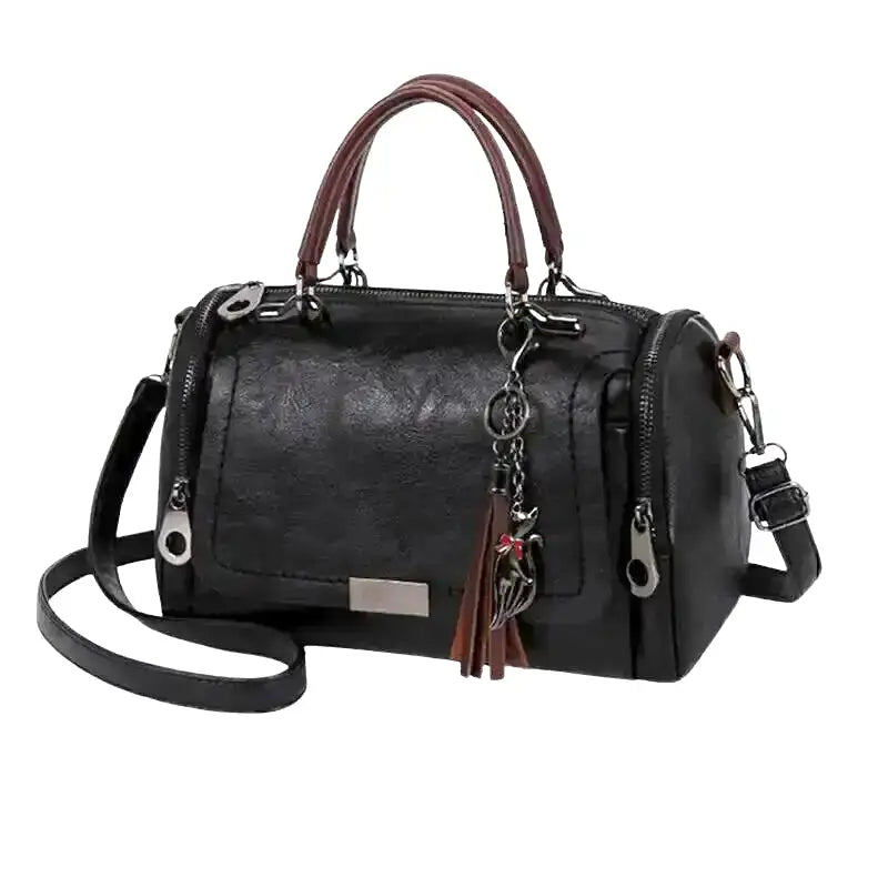 Modèle boston noir en cuir végan grainé, double poignée, bandoulière amovible et pompon