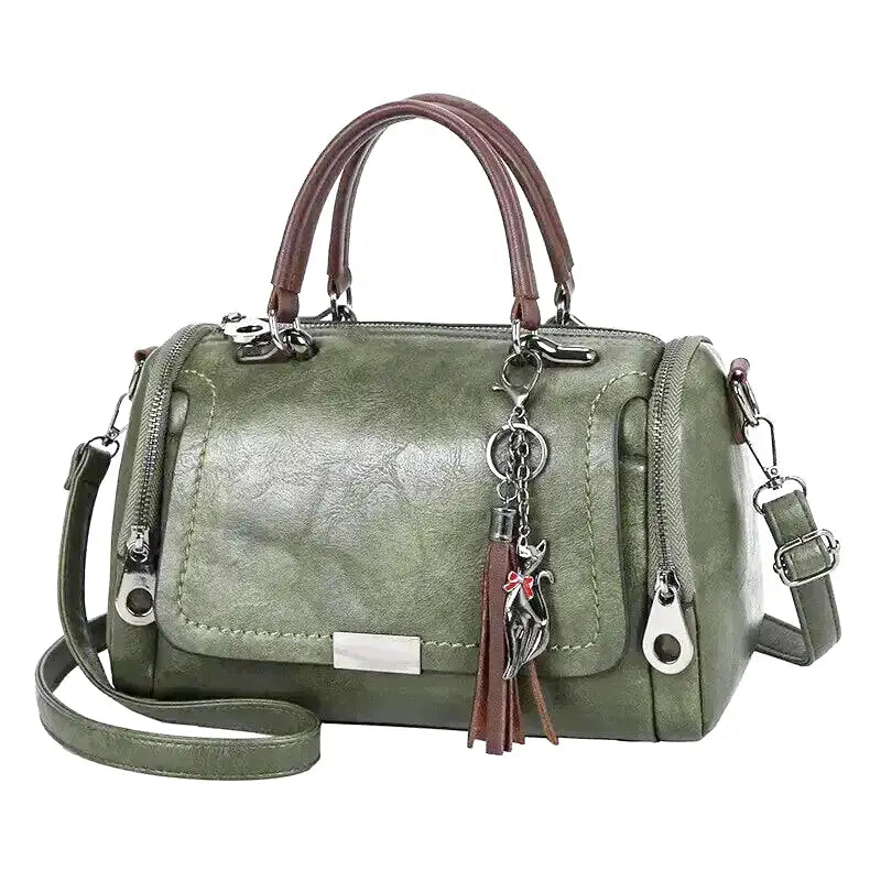 Vert sauge grisé, le sac boston aligne ses deux fermetures à glissière et sa plaque métal