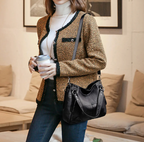 Croisé sur une veste en tweed beige, le hobo noir accompagne un jean droit et un col roulé