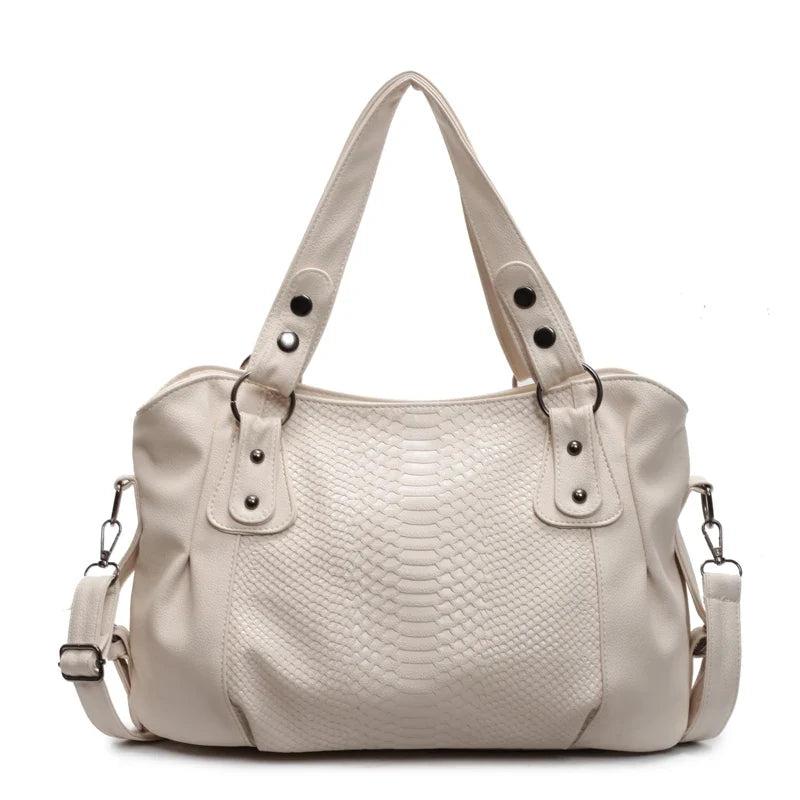 Écru, le grand sac souple à effet reptile aligne ses rivets métalliques et ses anses jumelles