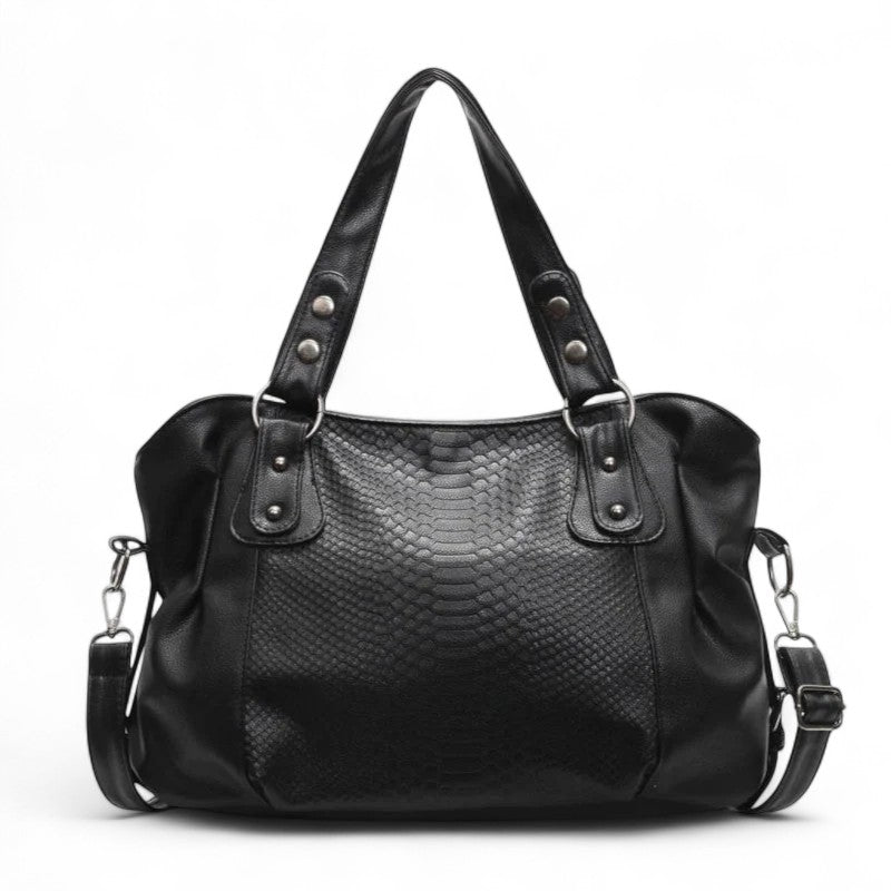 Sac cabas noir façon python, deux anses cloutées et bandoulière amovible, présenté de face