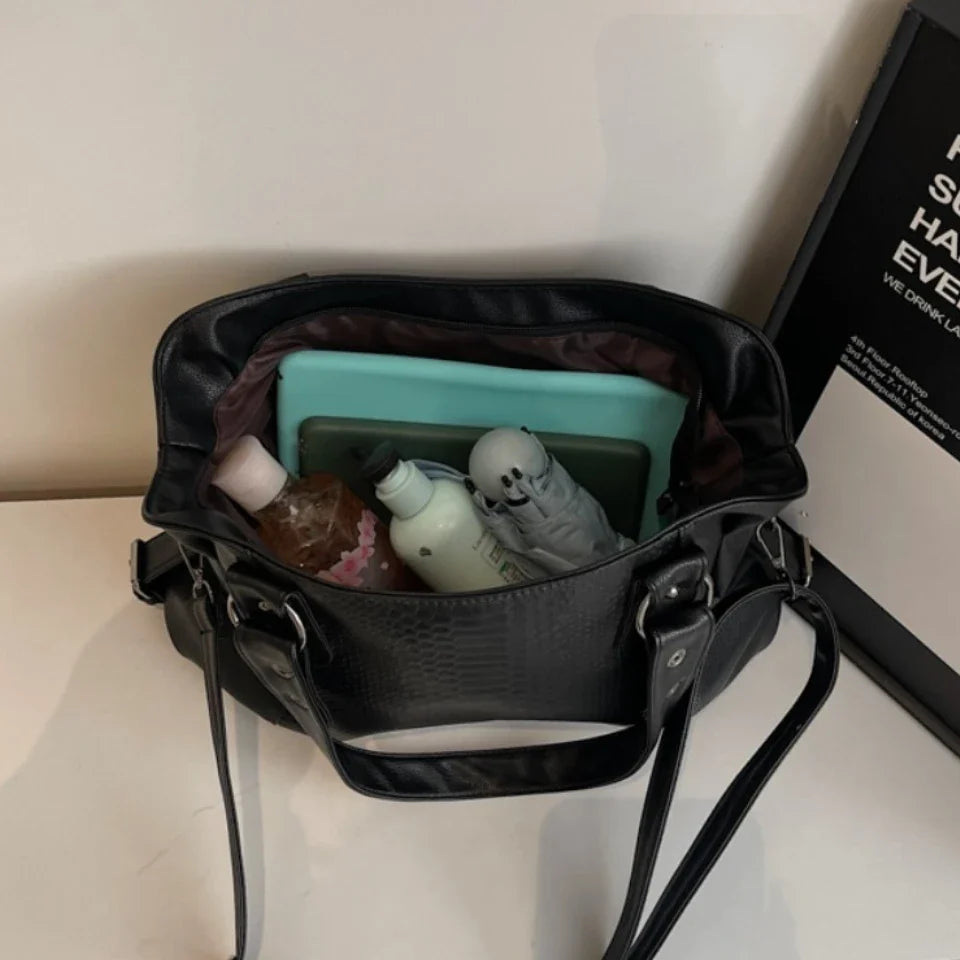 Intérieur du cabas noir ouvert, rempli d'une trousse, d'une boîte turquoise et de peluches