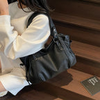 Épaule chargée du cabas noir, une étudiante en pull blanc assise dans un escalier en bois