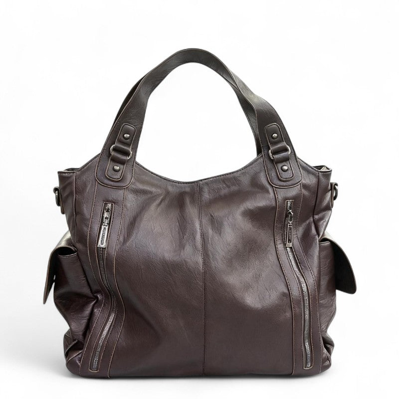 Brun café foncé, le sac se présente de face, anses courtes doublées et zips latéraux inclinés
