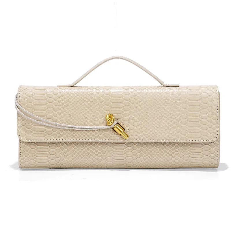 Beige crème gaufré croco, la pochette est présentée de face avec sa poignée souple et son fermoir