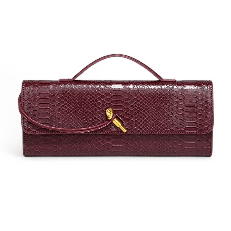 Pochette longue en cuir végan façon croco bordeaux, de face, anse plate et fermoir doré torsadé
