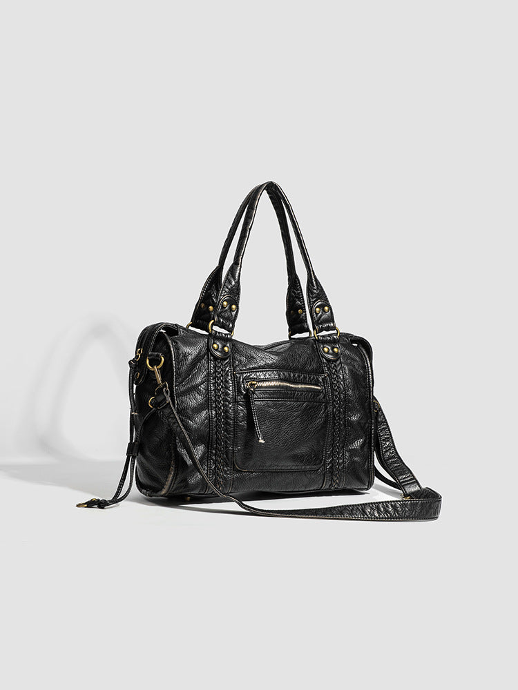 Longue bandoulière déployée au sol à droite du sac noir, mousquetons laiton et coulisses latérales