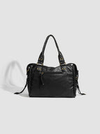 Face arrière du sac noir, panneau lisse et discrète poche zippée, sans les tresses de la façade