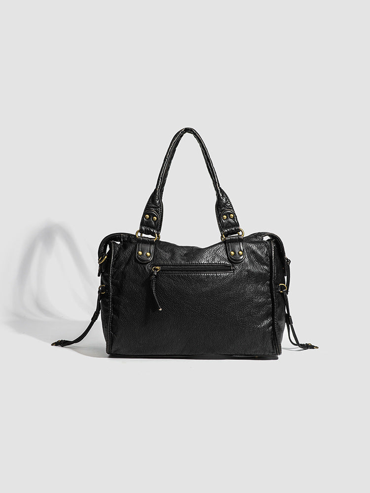 Face arrière du sac noir, panneau lisse et discrète poche zippée, sans les tresses de la façade