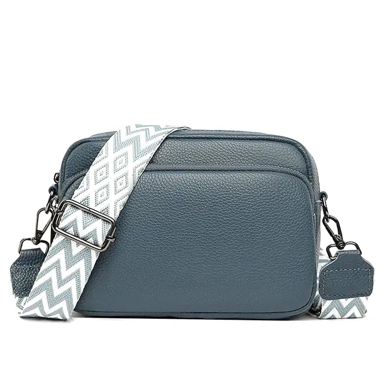 Bleu ardoise profond, ce petit sac rectangulaire s'accompagne d'une sangle à chevrons gris