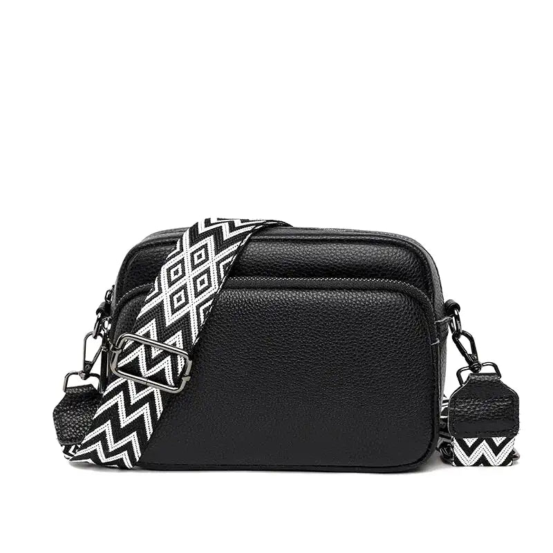Petite besace zippée noire au grain fin, large bandoulière à chevrons noirs et blancs