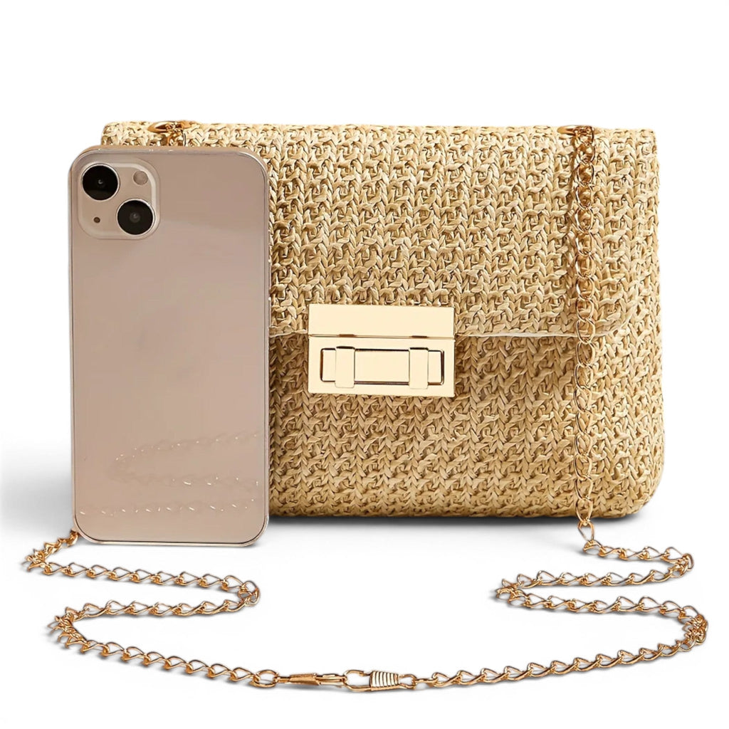Comparaison de taille avec un téléphone posé debout contre la pochette en paille dorée