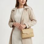 Silhouette en trench beige tenant la petite pochette en paille par sa chaîne dorée