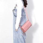 Croisée sur une salopette en jean, la pochette rose repose bas sur la hanche, sangle en diagonale