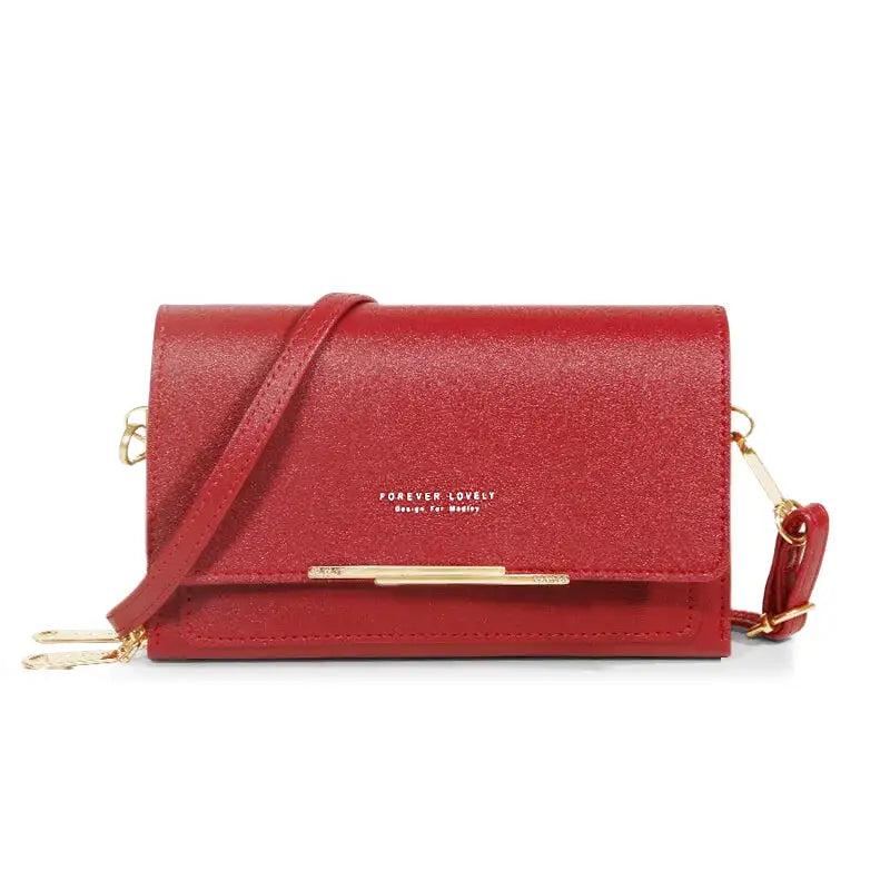 Rouge vif et légèrement grainé, ce sac bandoulière compact ferme par un rabat à barrette dorée