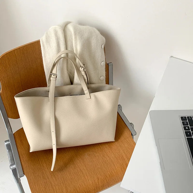 Posé sur une chaise en bois à côté d'un ordinateur portable, le cabas écru reste bien ouvert