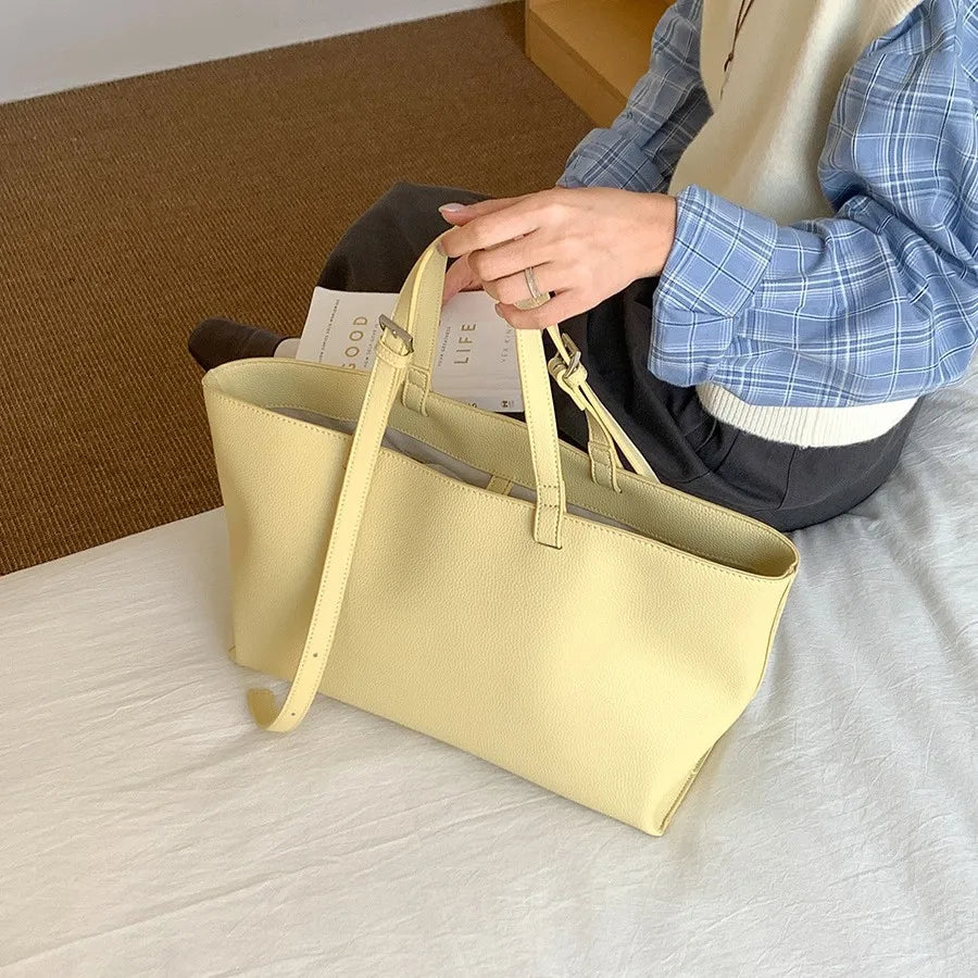 Rangement de feuilles dans le fourre-tout jaune pâle grand ouvert, posé sur un lit clair