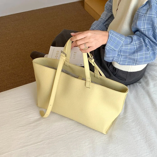 Rangement de feuilles dans le fourre-tout jaune pâle grand ouvert, posé sur un lit clair