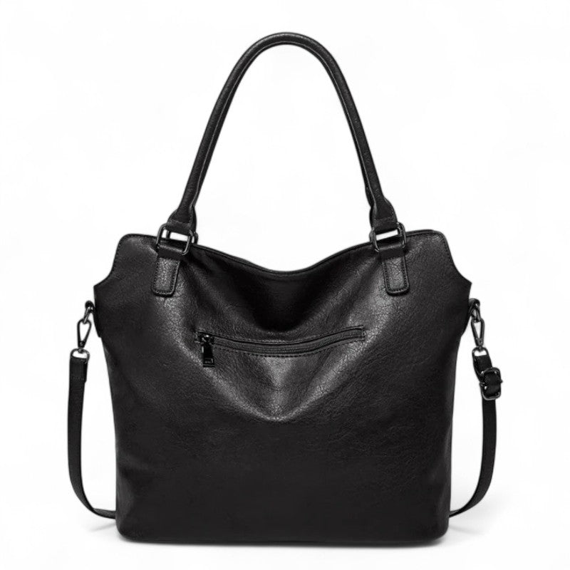 Revers du cabas noir, large poche zippée horizontale et sangle d'épaule accrochée sur le côté