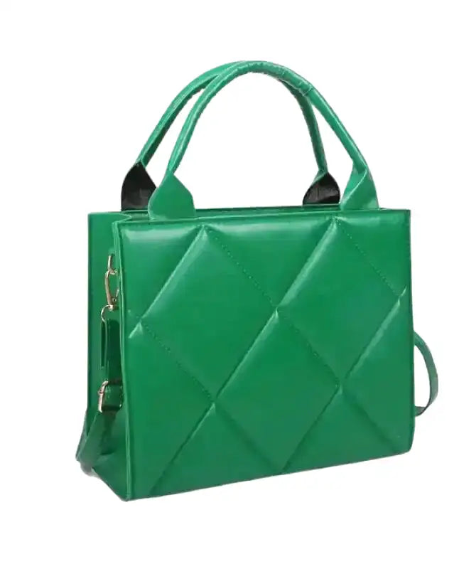 De trois quarts, le sac vert révèle son soufflet plat, son anse rigide et sa sangle amovible