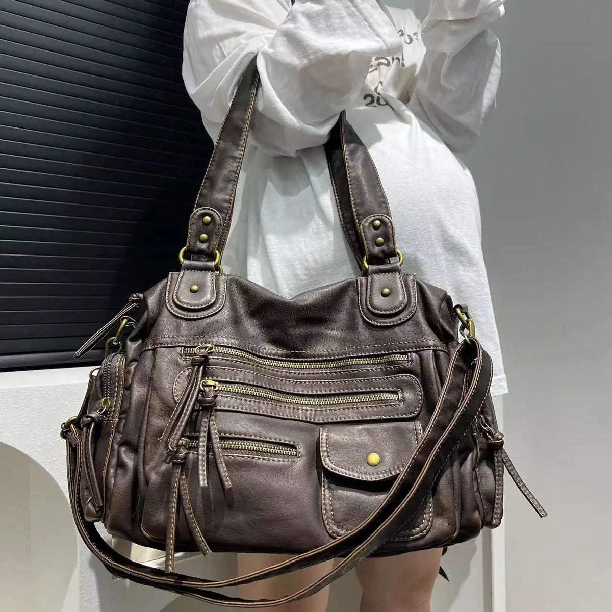 Bandoulière et anses réunies sur l'épaule, le hobo bronze irisé se porte sur une chemise blanche
