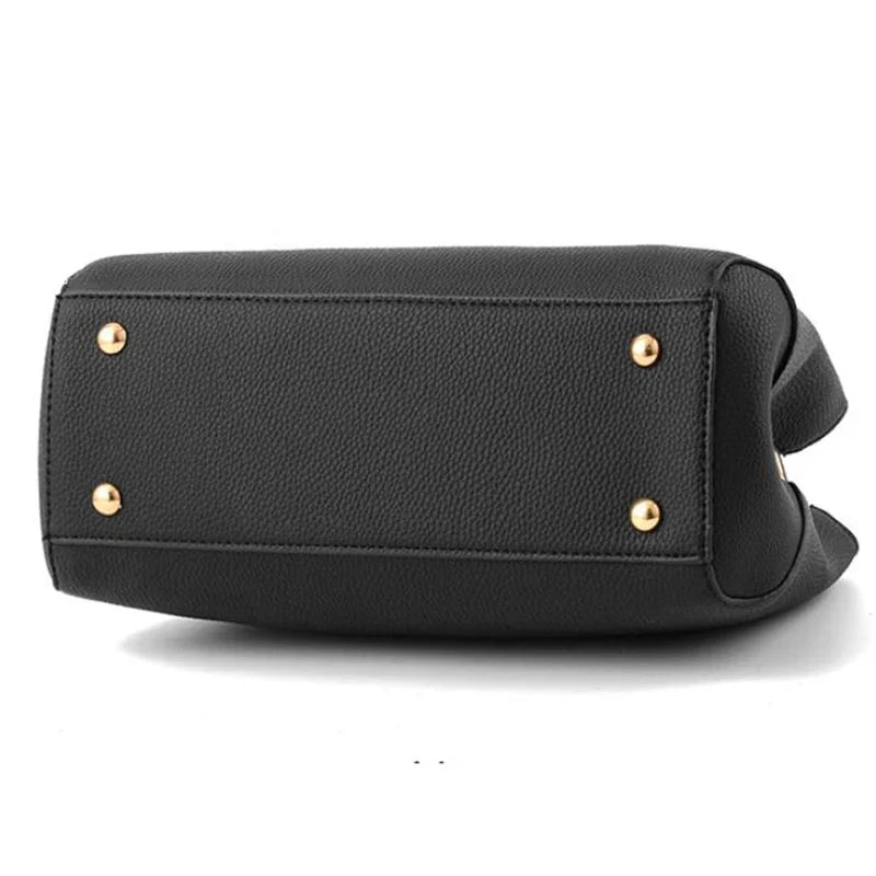 Fond du sac noir vu de dessous, quatre pieds métalliques dorés protégeant le cuir végan grainé