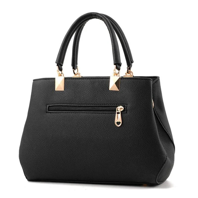 Dos du sac noir, entièrement lisse hormis une poche zippée horizontale à tirette dorée