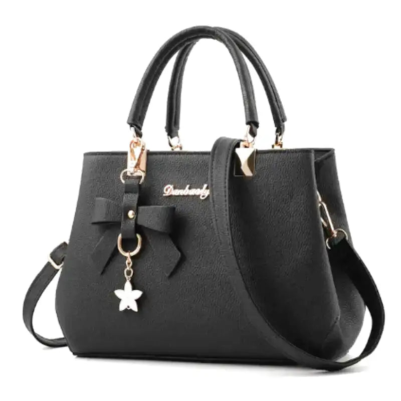 Sac à main noir en cuir végan à grain fin, vu de face, nœud décoratif et breloque étoile dorée