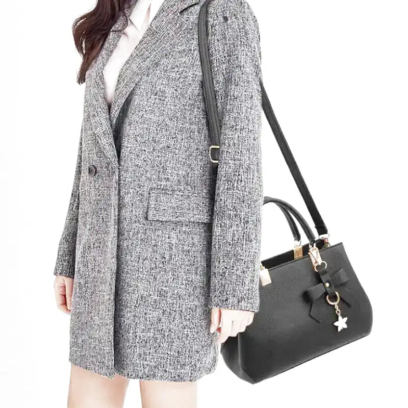 À l'épaule d'un modèle en manteau gris chiné, le sac noir tombe au niveau de la hanche