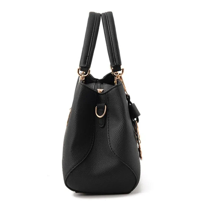 Profil du sac noir, base élargie, soufflets latéraux pincés et attache de bandoulière en anneau