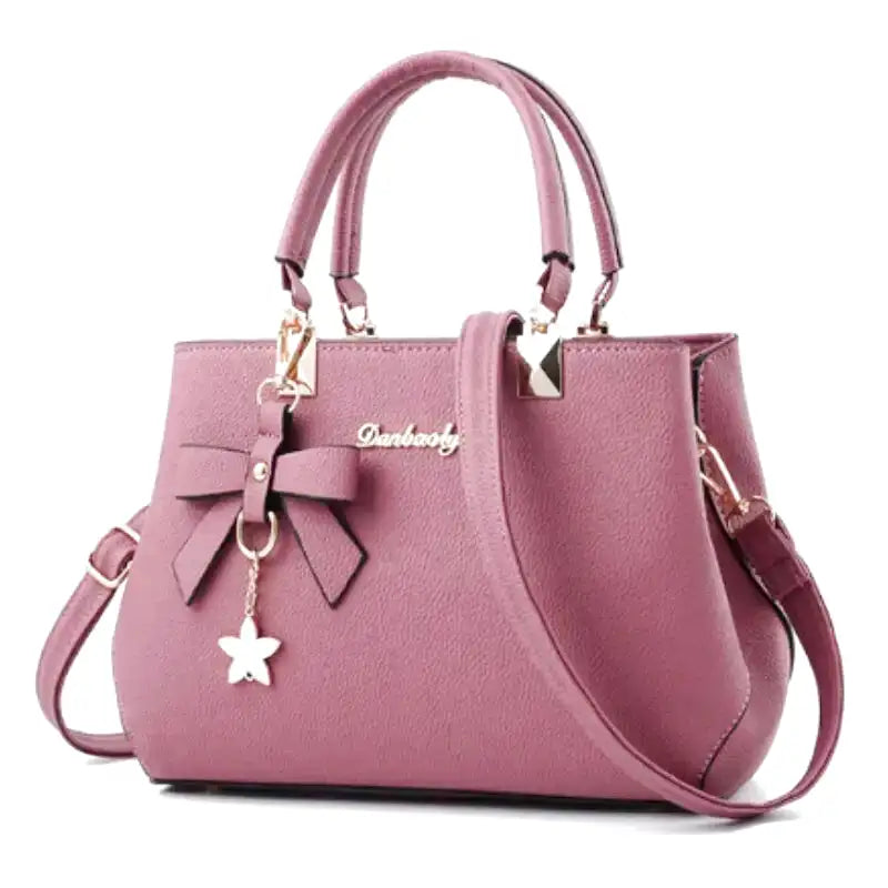 Vieux rose poudré sur ce sac à main à deux anses, vu de face, bandoulière fine et nœud assorti