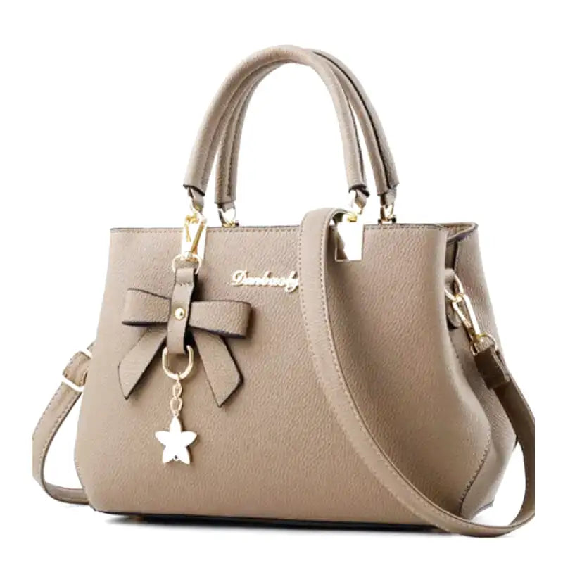 Beige grège clair et non brun, le sac à main structuré est vu de face, nœud et breloque étoile