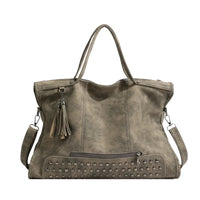 Grand cabas en cuir végan gris taupe, bas clouté, pompon à franges et bandoulière amovible