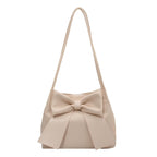 Nœud surdimensionné sur ce sac seau écru en cuir végan souple, longue bandoulière fine