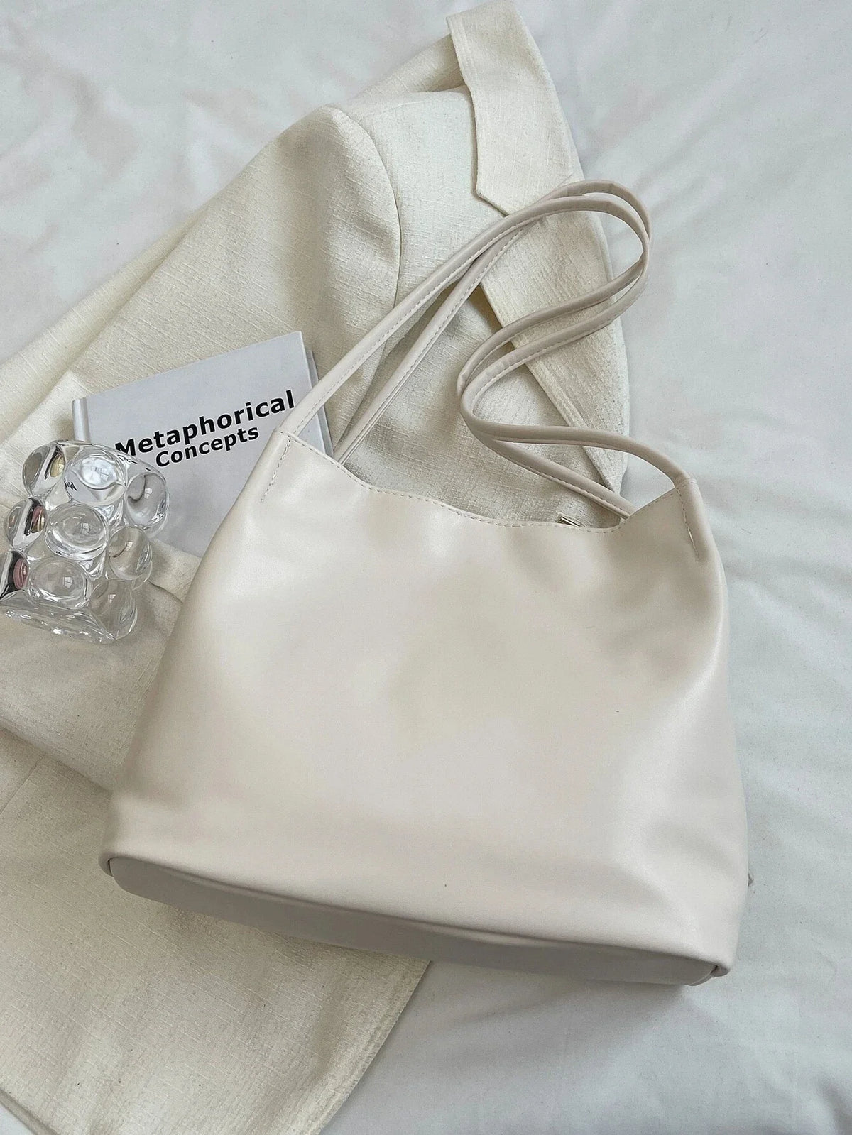 Posé à plat sur un drap blanc près d'une carte, le sac écru montre ses anses doubles