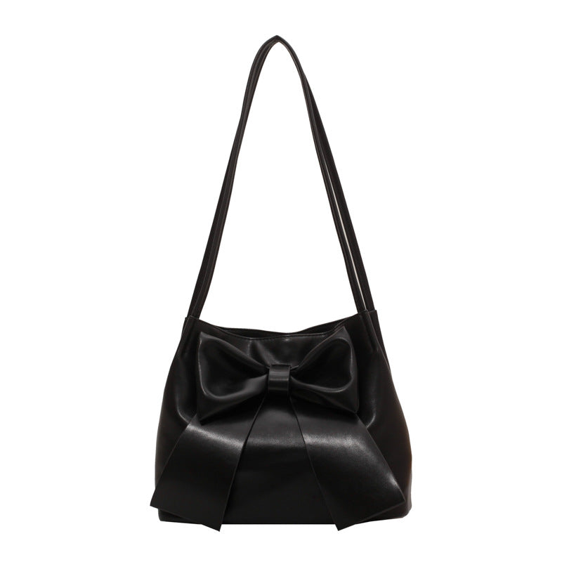 Noir mat, le sac à nœud se présente de face, plis marqués sur le bas et bandoulière longue