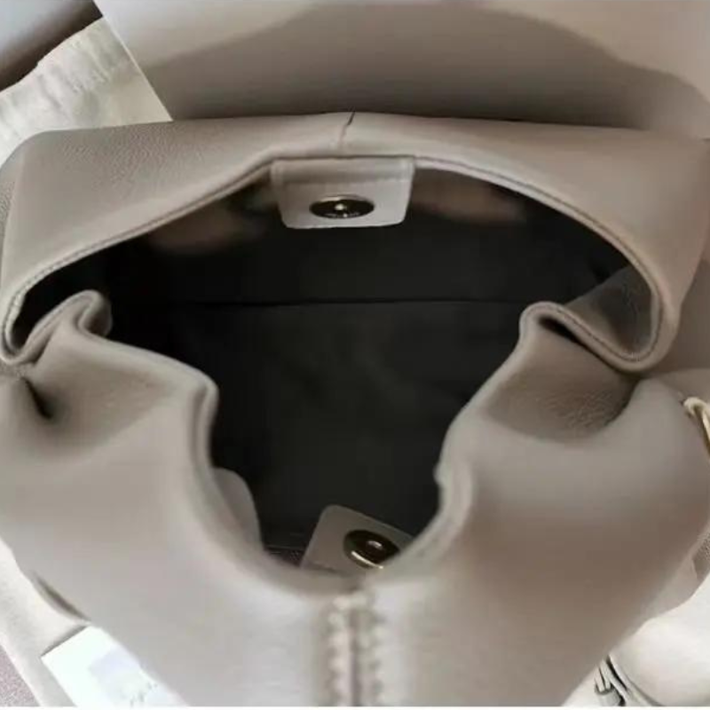 Ouverture du sac sur une doublure noire, fermoir aimanté doré et fronces du haut bien visibles