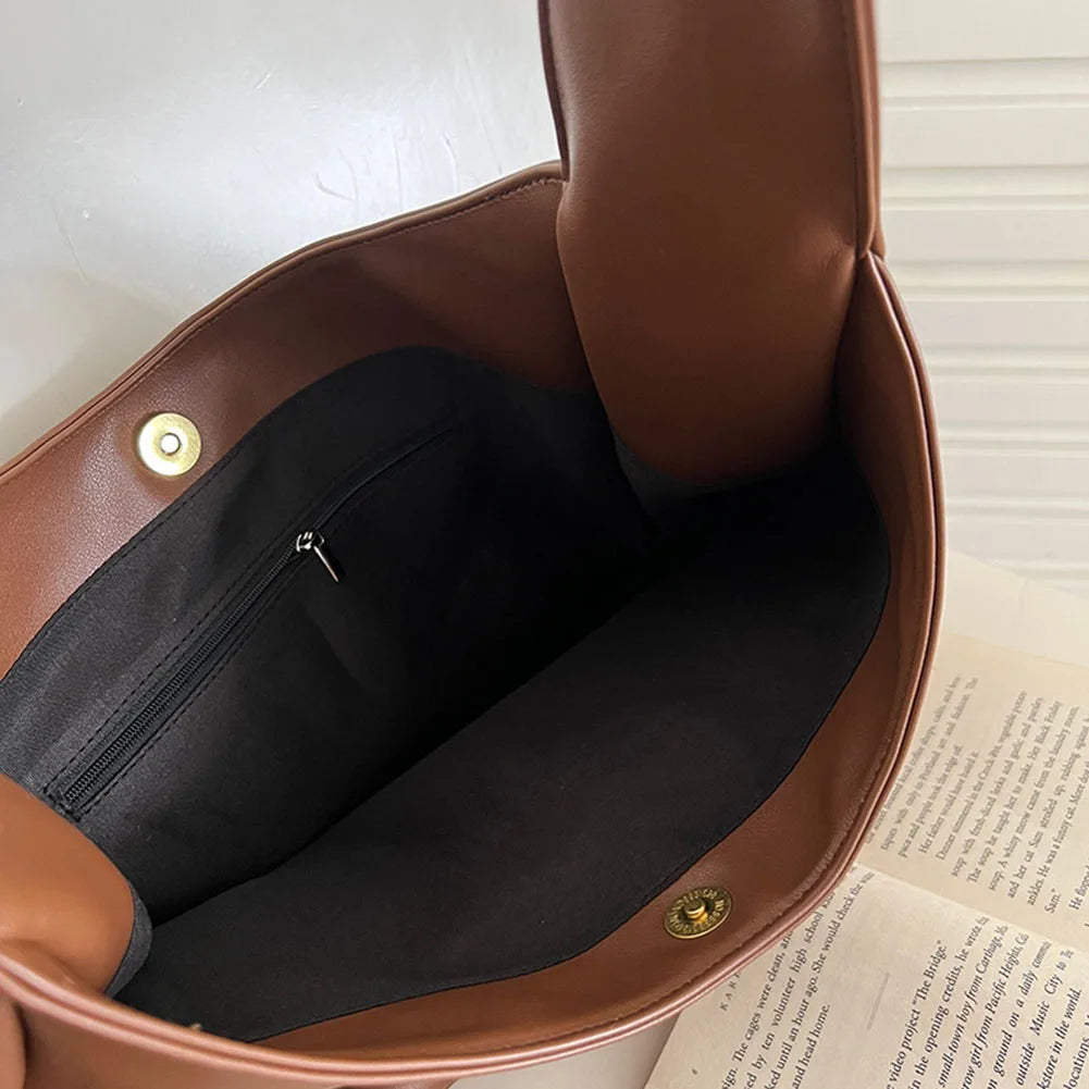 Ouvert sur sa doublure noire, l'intérieur révèle une poche zippée et un fermoir aimanté doré