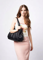 Serré contre la taille, le même sac noir accompagne un top clair et une jupe rose ajustée