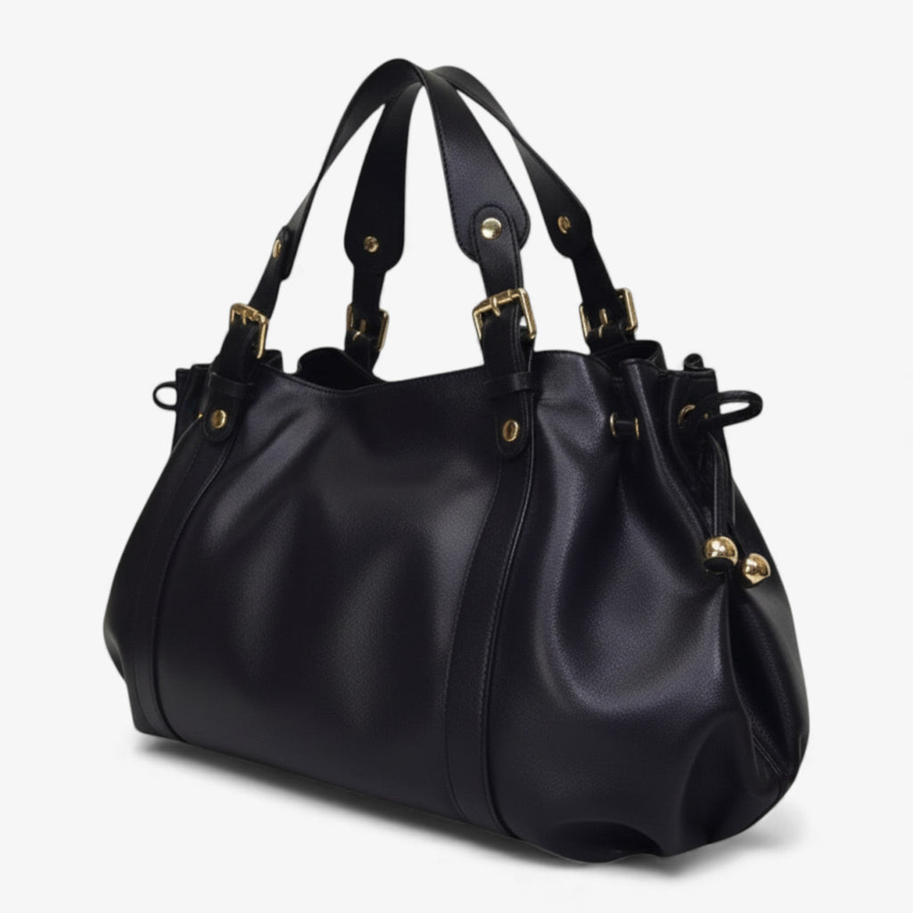 Sur fond blanc, le sac noir se présente de trois quarts, plis souples et liens à embouts dorés