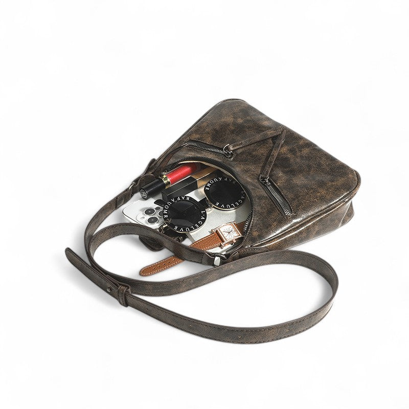 Contenu répandu : appareil photo, montre et rouge à lèvres sortant du petit sac brun ouvert