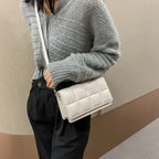 Petit sac blanc cassé porté en croisé sur un gilet gris chiné et un pantalon noir, mains libres