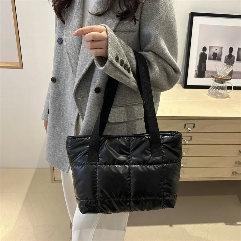 Tenu par les anses devant un manteau gris, le cabas noir matelassé garde tout son volume