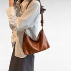 Épaulé sur une chemise écrue, le sac baguette marron châtaigne suit la ligne du buste