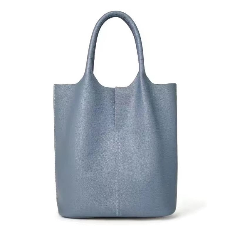 Bleu gris clair, ce tote au cuir végan grainé se tient de face, anses souples et flancs bien droits