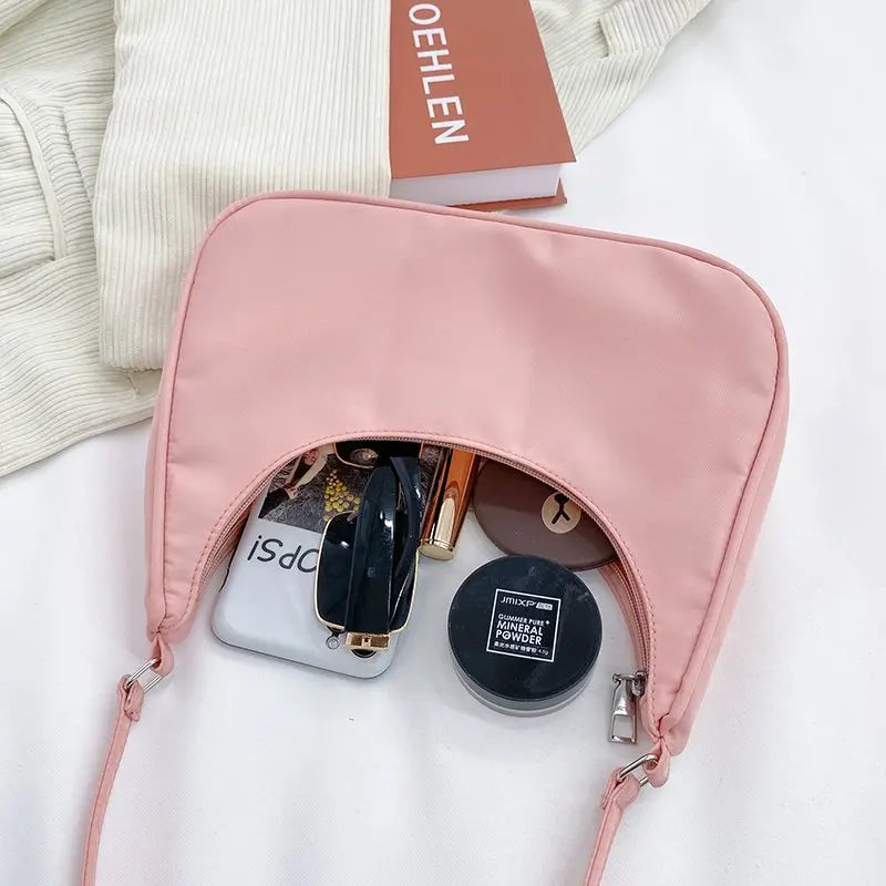 Ouverte sur un miroir, un poudrier et des clés, la pochette rose révèle sa contenance