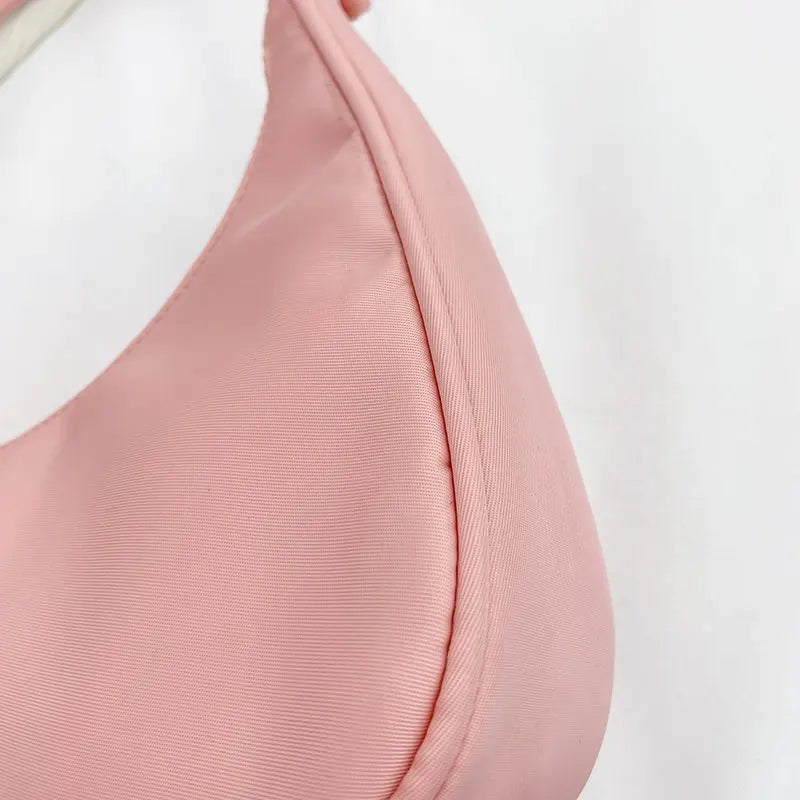 Gros plan sur la toile rose légèrement côtelée et sur la couture arrondie du fond du sac