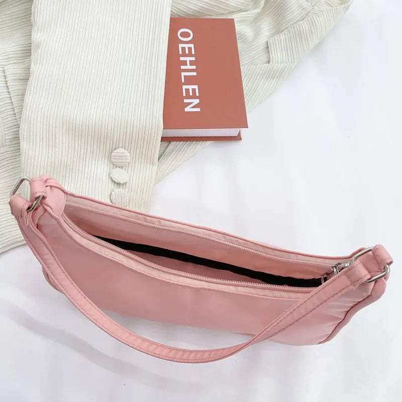 Pochette rose posée à plat près d'un magazine, glissière ouverte sur toute la longueur