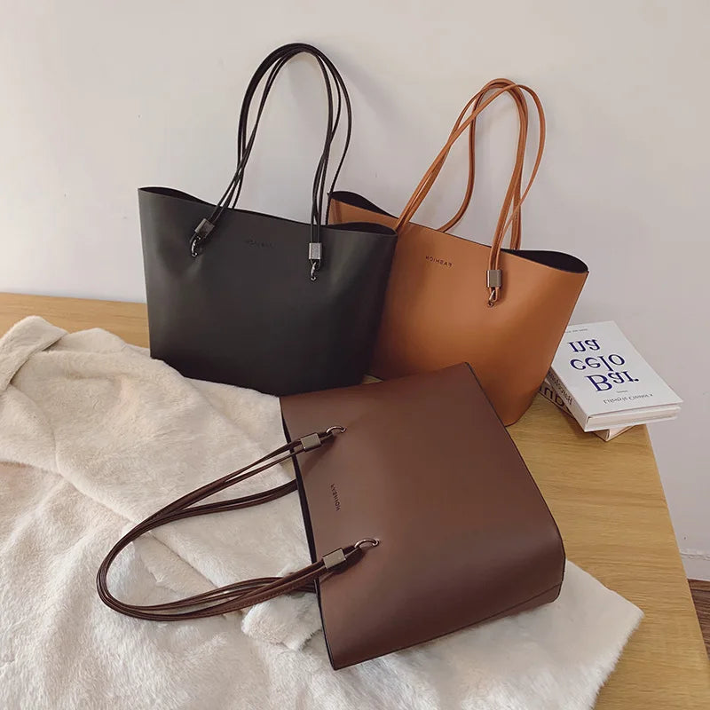 Trois coloris réunis sur un plaid clair : gris anthracite, camel et brun foncé, anses fines