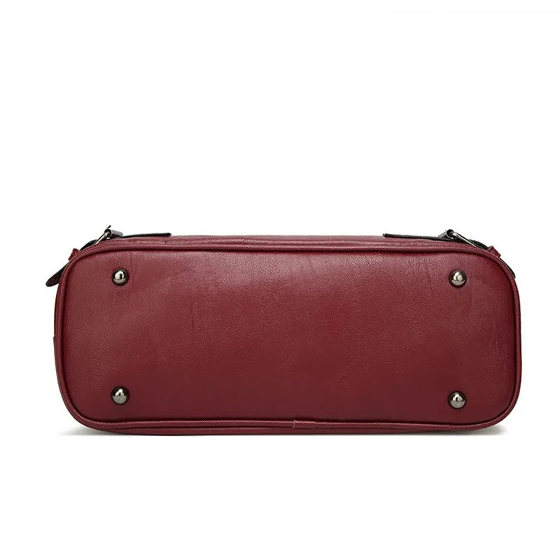 Base rectangulaire du sac bordeaux vue de dessous, pieds métal et rivets aux quatre angles